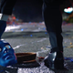 A blue man picking up a blue mask.